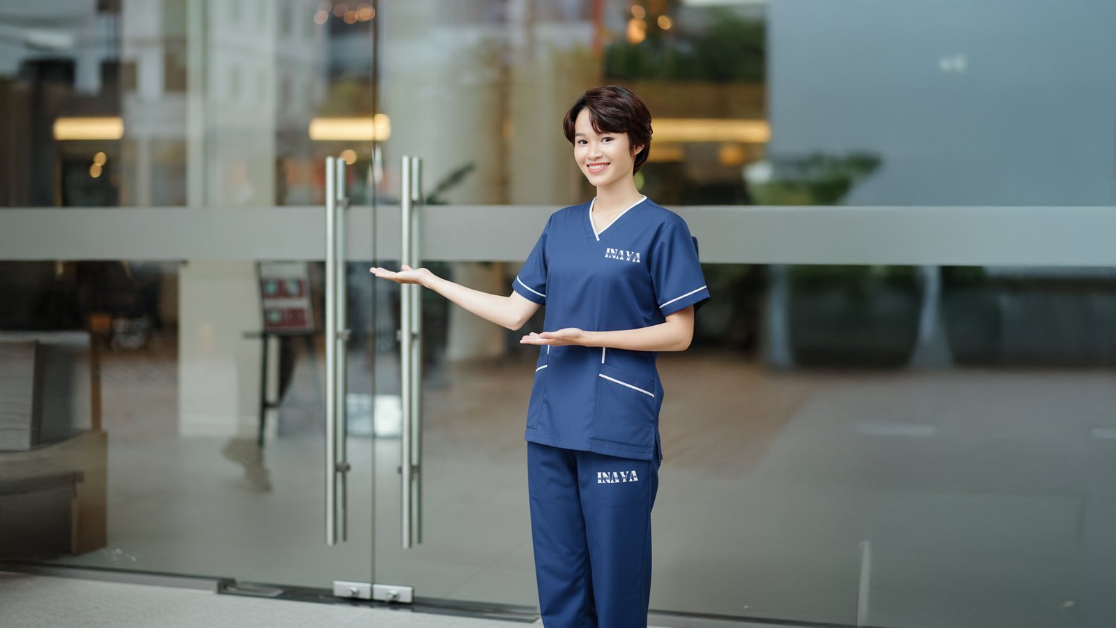 INAYA uniform by a glass entrance