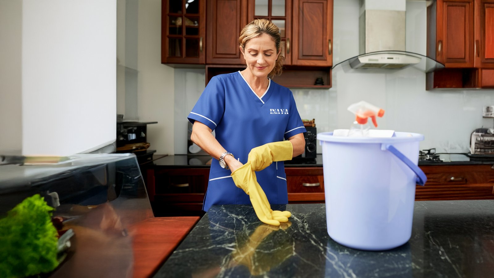 Wiping a kitchen counter beside a cleaning bucket