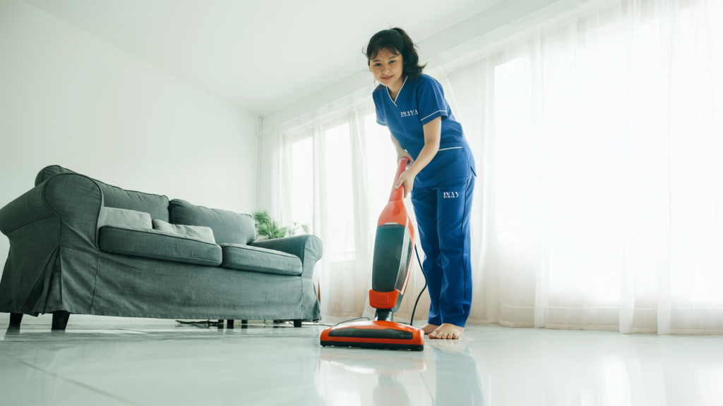 INAYA domestic worker vacuuming living room floor Ajman